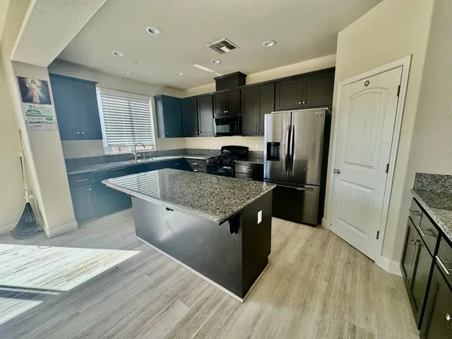 a kitchen with stainless steel appliances granite countertop a sink stove and refrigerator