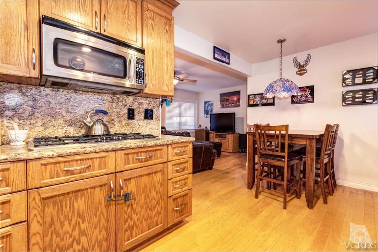 2273 Keystone Street Simi Valley, CA 93063 - Photo 13 of 29 a kitchen with stainless steel appliances granite countertop a stove top oven a dining table and chairs with wooden floor