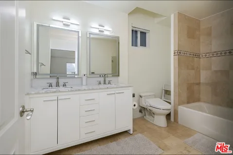 a bathroom with a toilet a sink a mirror a bathtub and shower