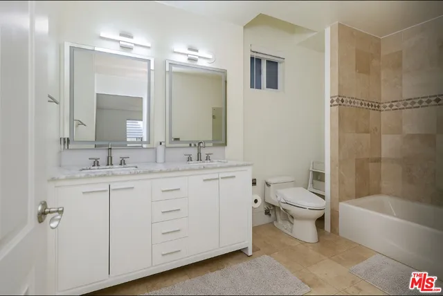 a bathroom with a toilet a sink a mirror a bathtub and shower