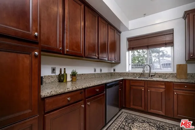 a kitchen with granite countertop stainless steel appliances a sink window and cabinets