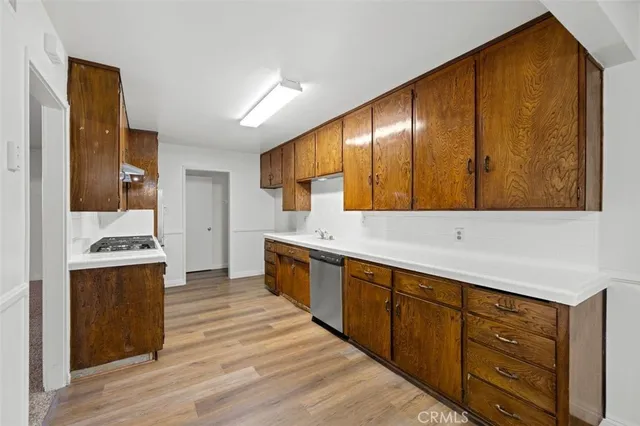 a large kitchen with stainless steel appliances wooden cabinets and a wooden floor