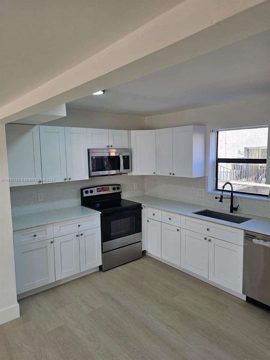 a kitchen with granite countertop a sink and white cabinets