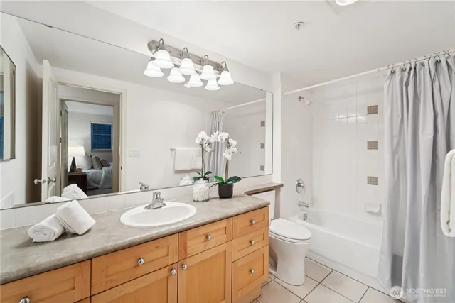a bathroom with a granite countertop sink a toilet mirror and shower