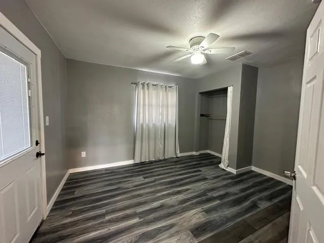 a view of an empty room with window and wooden floor