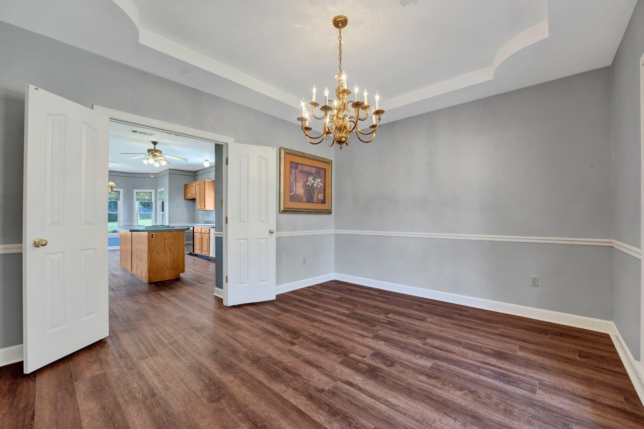 4149 Old Forest Road Memphis, TN 38125 - Photo 18 of 32 Empty room with dark hardwood / wood-style flooring, a raised ceiling, and ceiling fan with notable chandelier