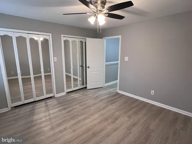 an empty room with wooden floor fan and windows