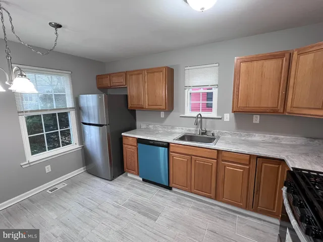 a kitchen with stainless steel appliances granite countertop a refrigerator sink and wooden cabinets