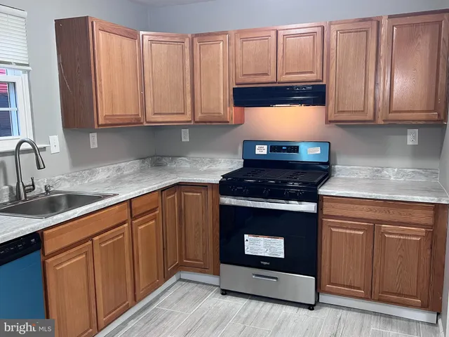 a kitchen with granite countertop a stove top oven sink and cabinets