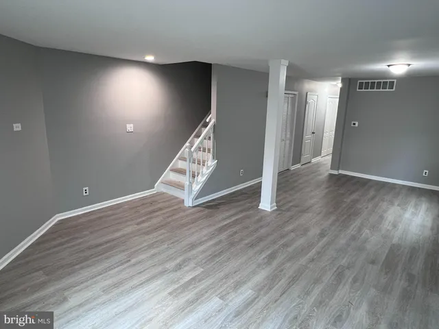 an empty room with wooden floor and staircase
