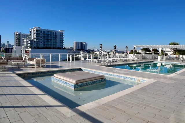 a view of a swimming pool with outdoor seating and buildings in the background