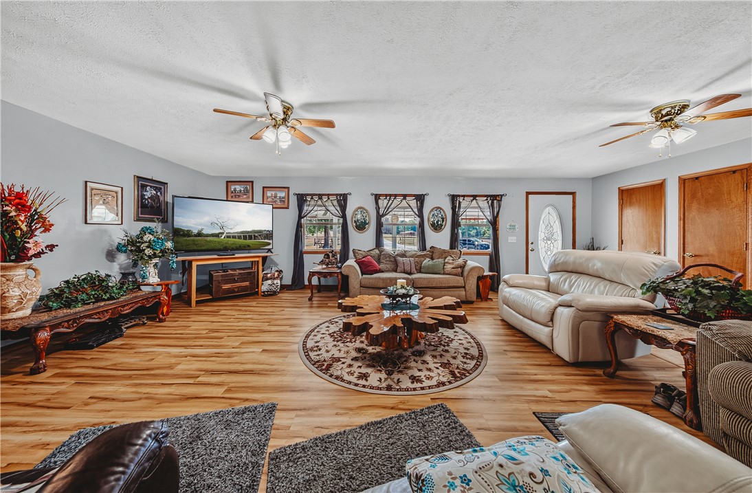 21587 West Hickory Flat Road Springdale, AR 72764 - Photo 12 of 45 Generously sized living room with abundant natural light, multiple ceiling fans, wood flooring, and flexible seating options.