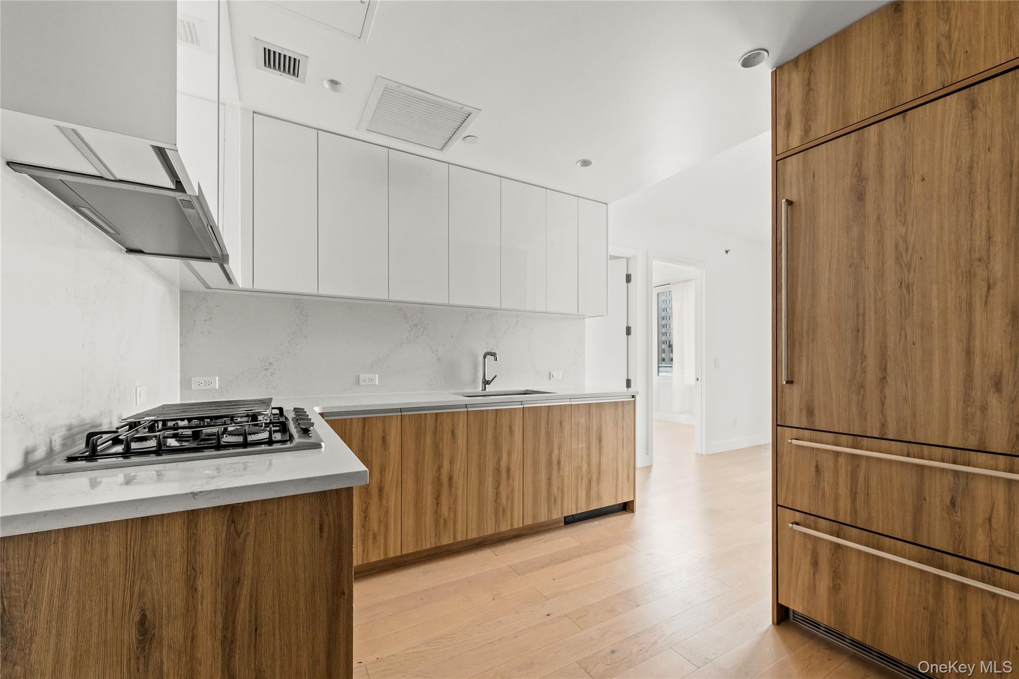 13618 Maple Avenue, Unit 5F Queens, NY 11355 - Photo 9 of 41 Kitchen featuring brown cabinetry, modern cabinets, white cabinetry, light wood-style floors, and paneled built in fridge