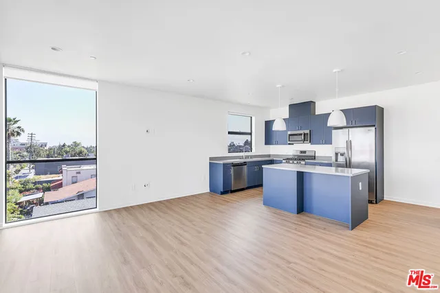 a large kitchen with stainless steel appliances wooden floors and large cabinets