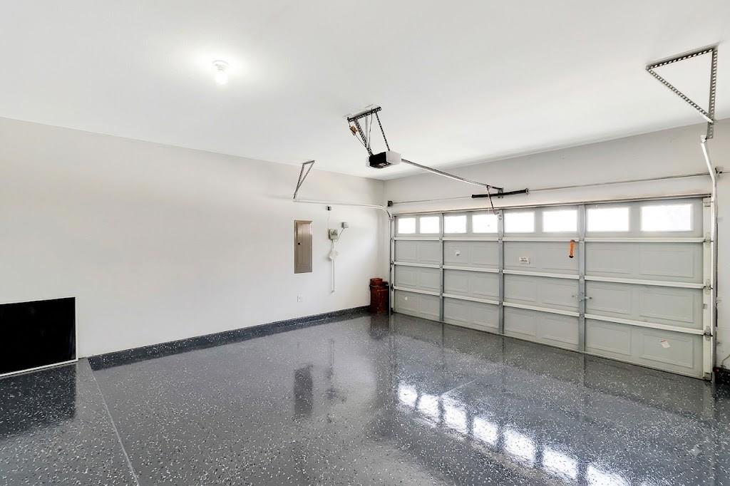 4908 Rushden Road McKinney, TX 75070 - Photo 32 of 34 Spacious garage featuring a durable epoxy floor, an automatic overhead door with integrated windows, and a ceiling-mounted light fixture