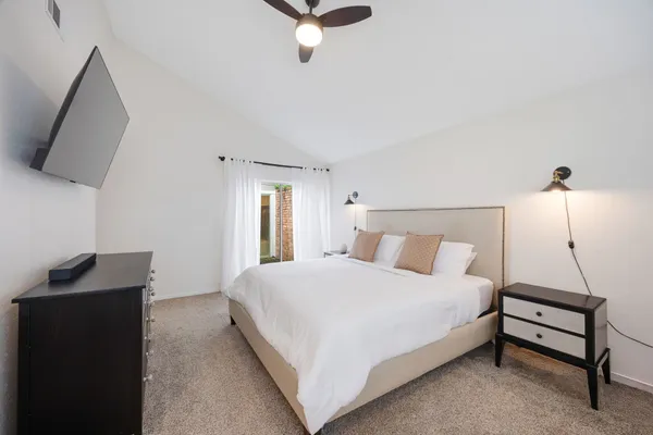 a bedroom with a bed and a flat tv screen on the dresser