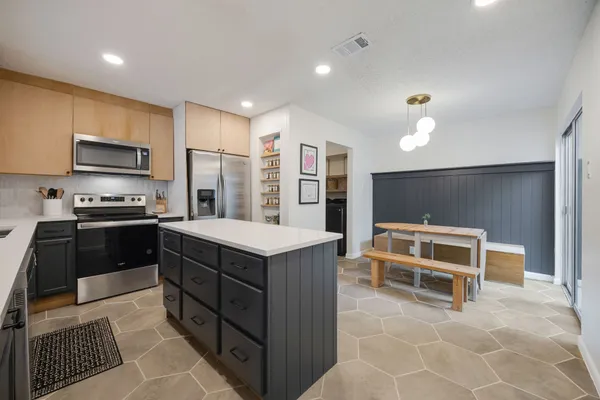 a kitchen with a refrigerator a stove top oven and cabinets