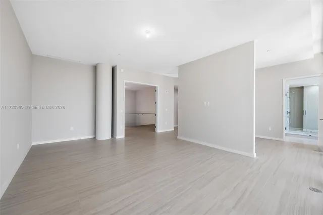 a view of an empty room with wooden floor and closet