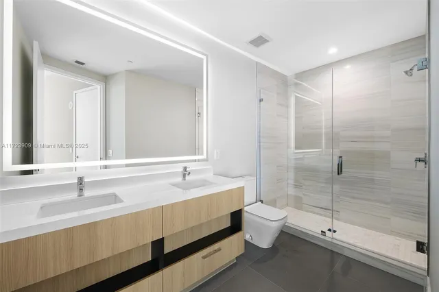 a bathroom with a double vanity sink toilet and shower