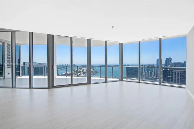 a view of an empty room with wooden floor and windows