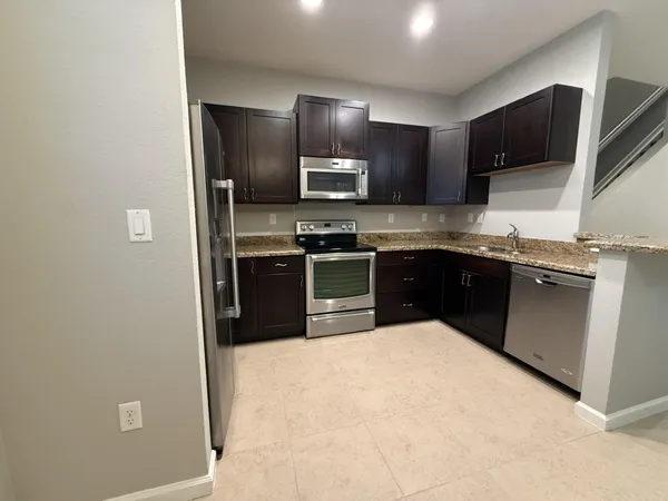 a kitchen with stainless steel appliances granite countertop a sink stove and refrigerator