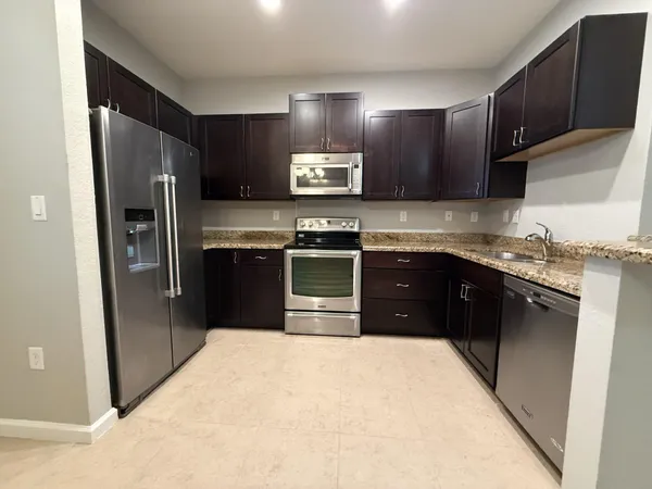 a kitchen with stainless steel appliances granite countertop a refrigerator a stove a sink and a microwave