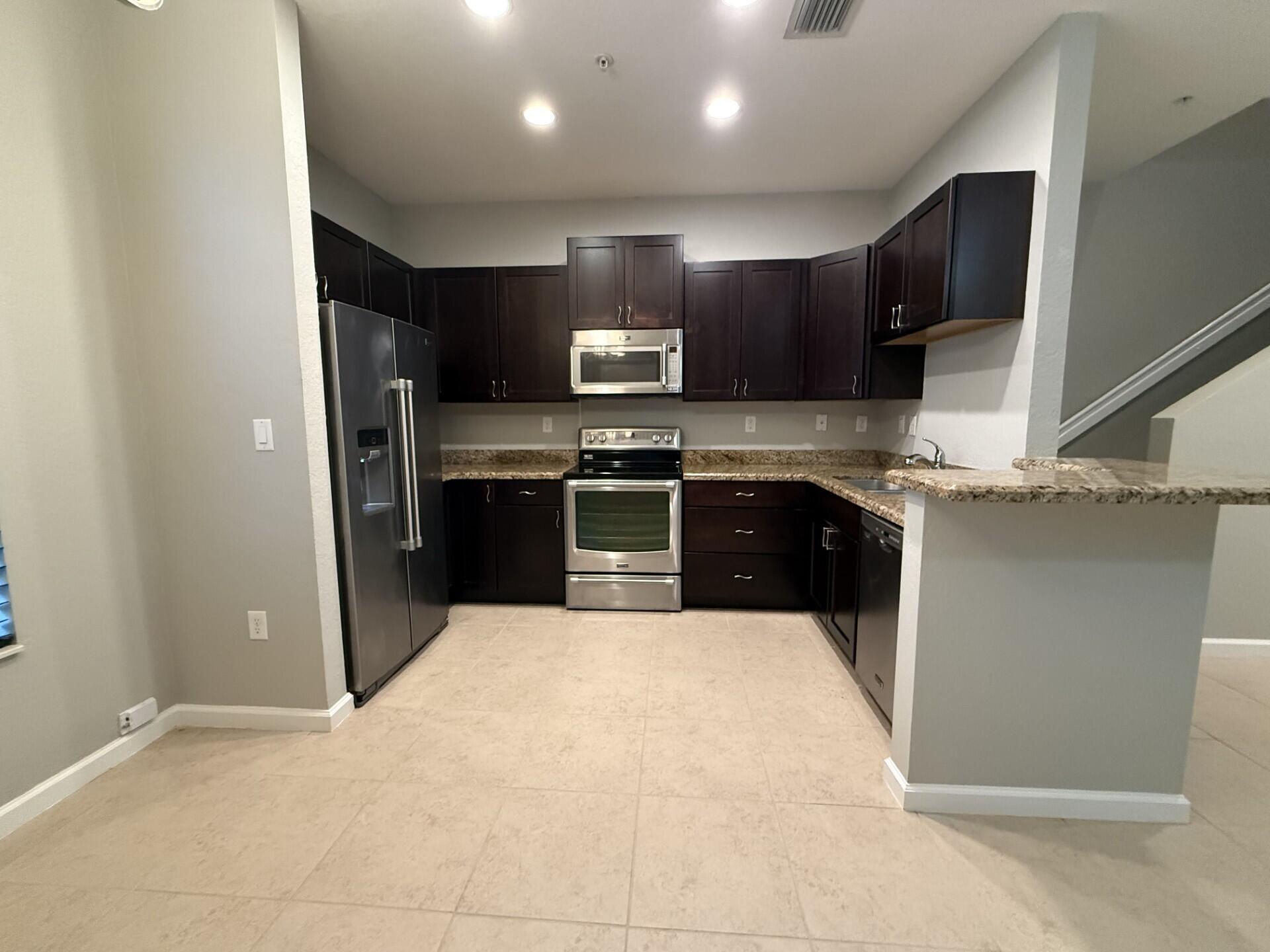 704 Southwest 2nd Way Pompano Beach, FL 33060 - Photo 6 of 22 a kitchen with stainless steel appliances granite countertop a sink stove and refrigerator