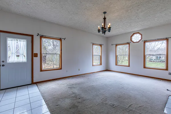 an empty room with windows and chandelier fan