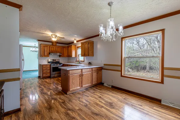 a kitchen with stainless steel appliances granite countertop a stove top oven a refrigerator a dining table and chairs with wooden floor