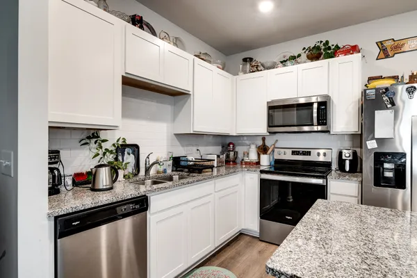 a kitchen with granite countertop a sink dishwasher stove and microwave with wooden floor