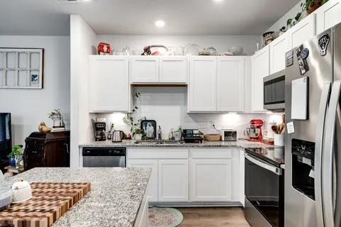 a kitchen with granite countertop a sink stainless steel appliances and white cabinets