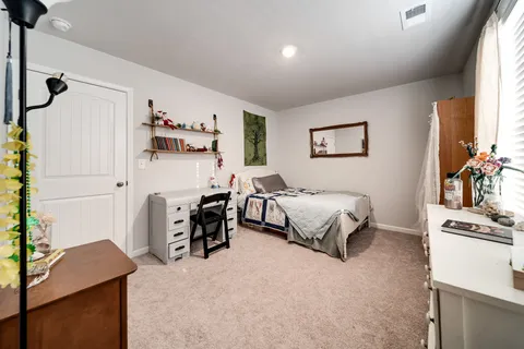 a bedroom with a bed and a flat tv screen on dresser