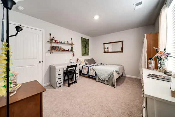 a bedroom with a bed and a flat tv screen on dresser