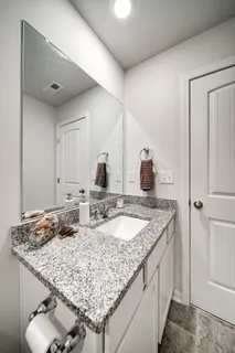 a bathroom with a granite countertop sink and a mirror