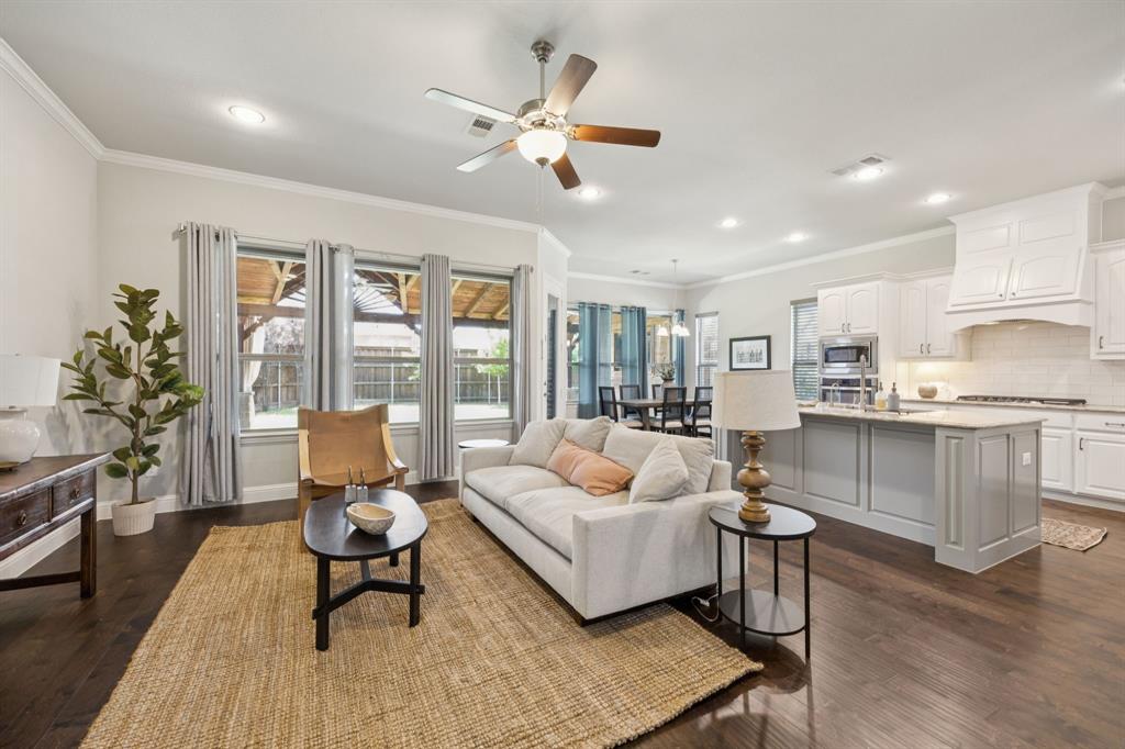 Living area featuring dark wood-type flooring, ceiling fan, crown molding, and recessed lighting