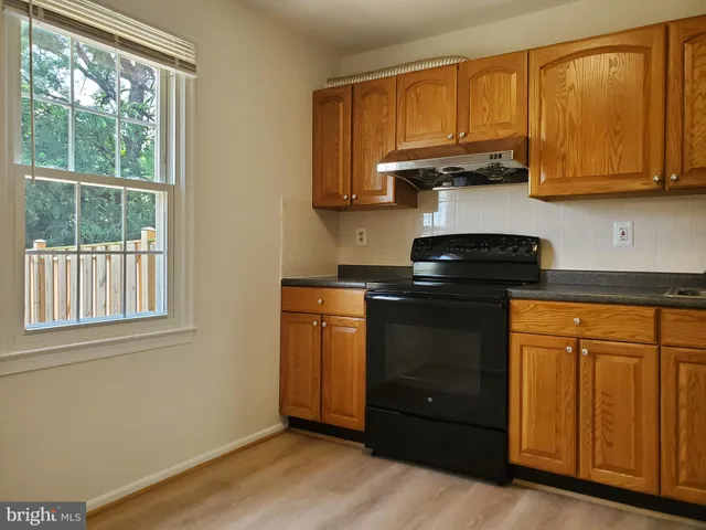 a kitchen with stainless steel appliances granite countertop wooden cabinets and a stove top oven