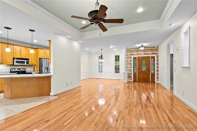 a view of an empty room and kitchen with stainless steel appliances wooden floor