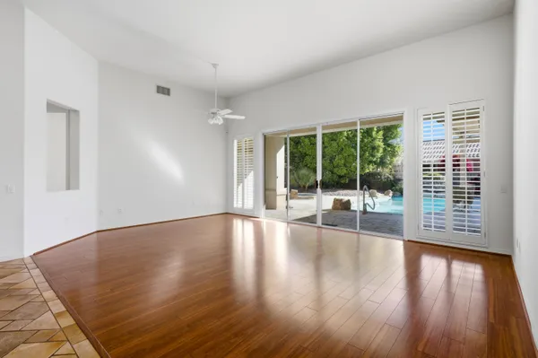 an empty room with wooden floor mirror and windows