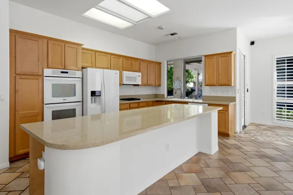 a kitchen with granite countertop a sink a stove a refrigerator a white stove top oven and cabinets