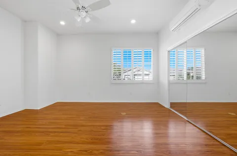 an empty room with wooden floor cabinet and windows