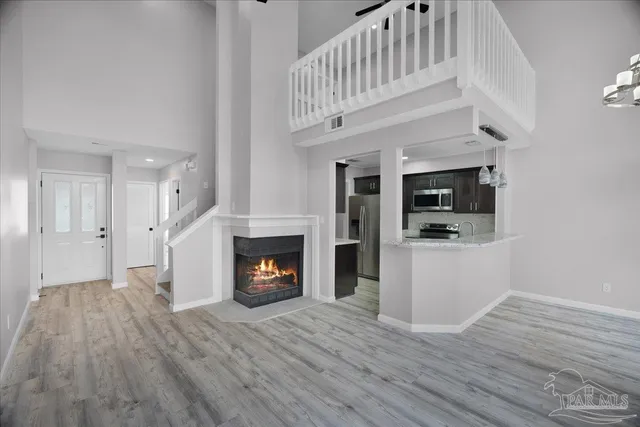 a view of an empty room with wooden floor fireplace and a window