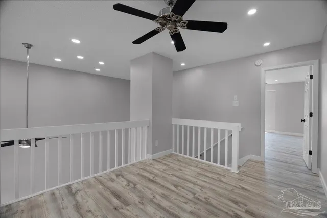 an empty room with wooden floor fan and windows