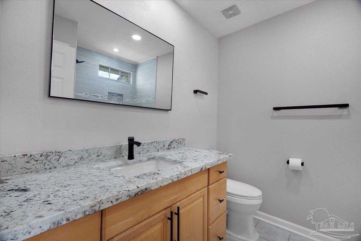 601 East Burgess Road, Unit J2 Pensacola, FL 32504 - Photo 23 of 38 a bathroom with a granite countertop sink vanity mirror and toilet