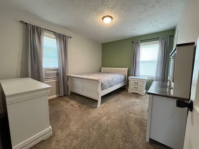 a living room with a bed and a flat tv screen on dresser