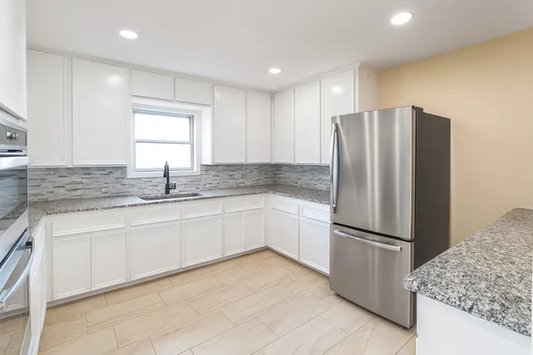a kitchen with stainless steel appliances granite countertop a refrigerator and a sink