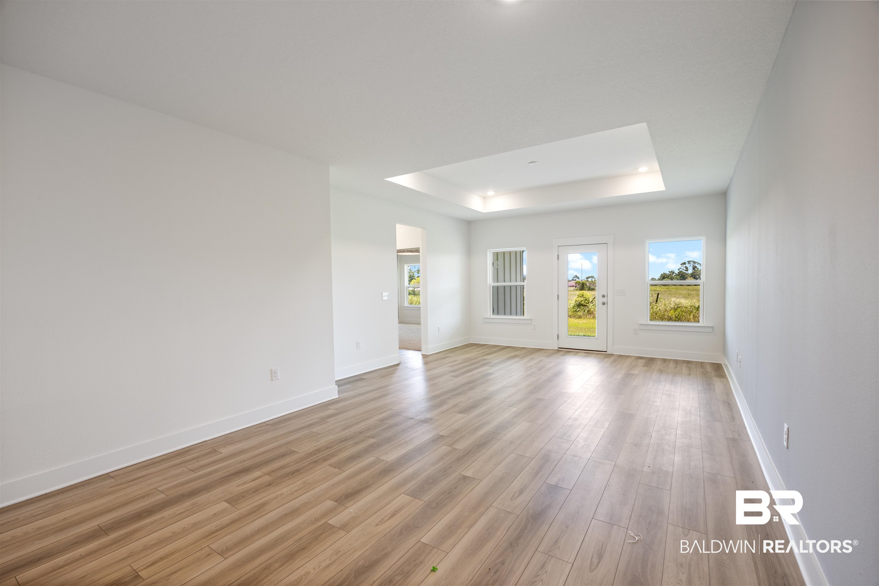 9986 Weller Cove Foley, AL 36535 - Photo 15 of 43 Unfurnished living room featuring a tray ceiling, plenty of natural light, and light wood-style flooring