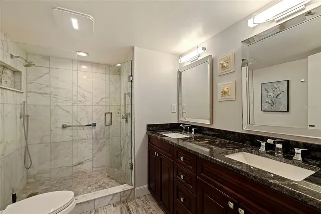 a bathroom with a granite countertop sink toilet a mirror and shower