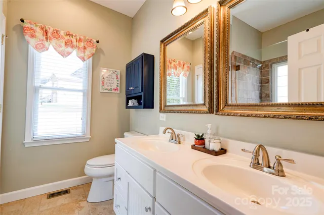 a bathroom with a sink vanity granite toilet and a mirror