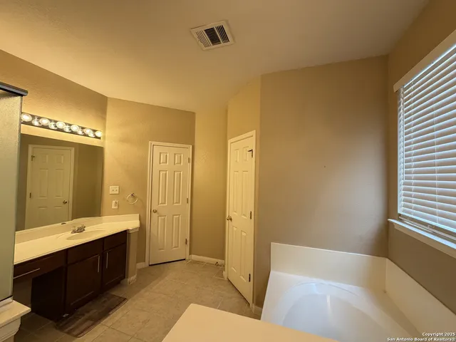 a bathroom with a tub sink shower and two mirror