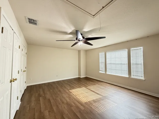 a view of an empty room with a window and wooden floor